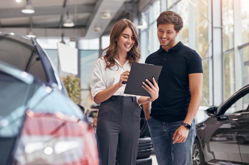 Allane Auto-Leasing: Mann und Frau im Autohaus diskutieren Angebot